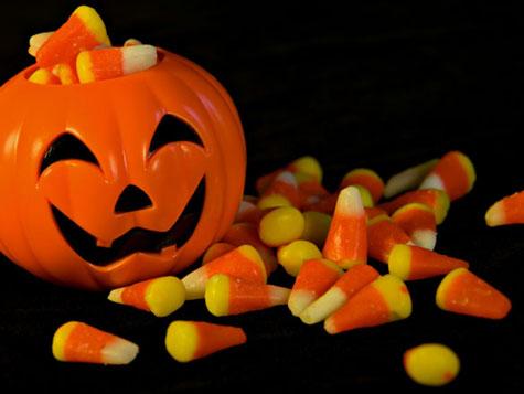 picture of a glass pumpkin with scattered candy corn next to it